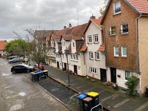 A row of traditional European-style houses with sloped roofs, a paved street, and parked cars.