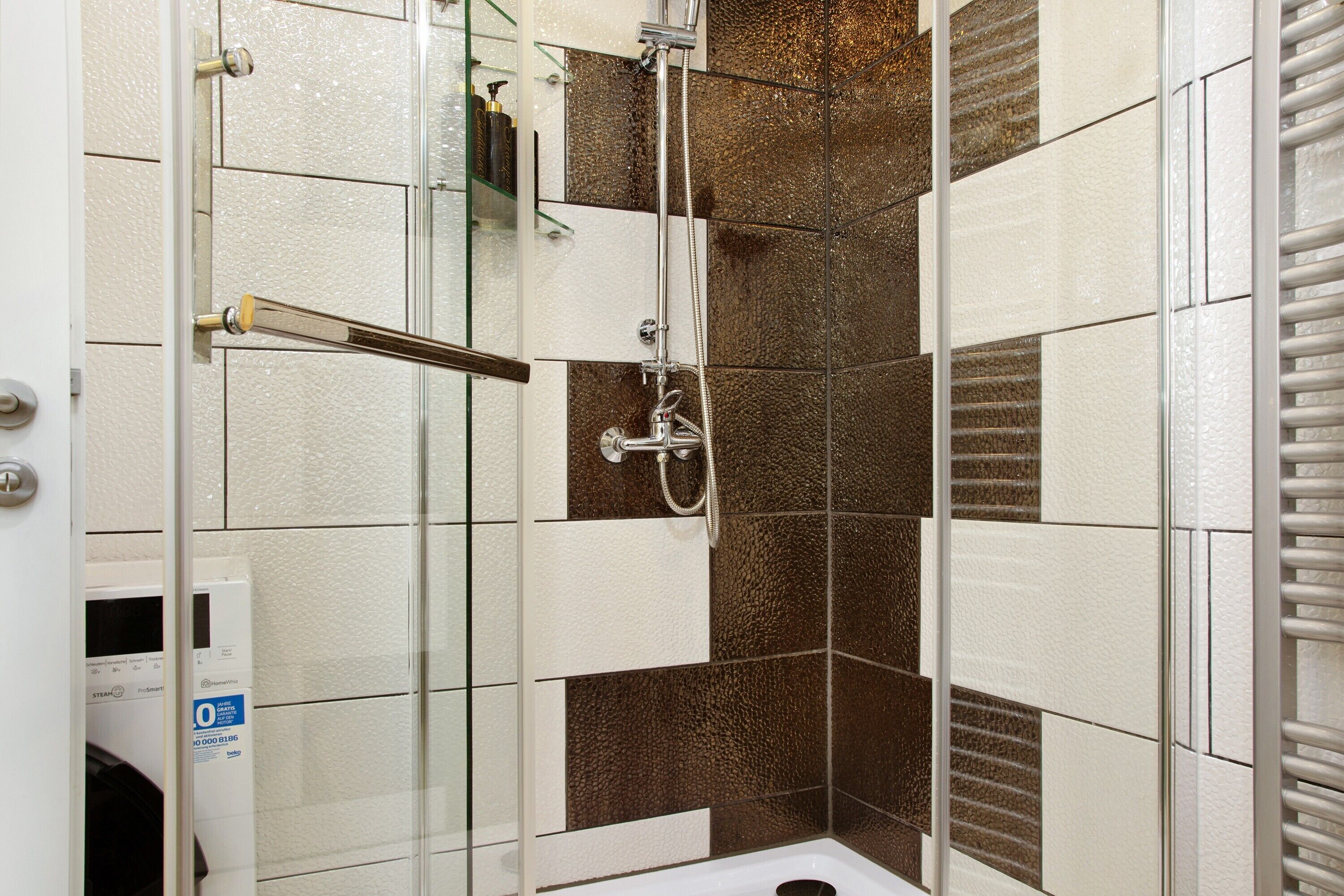 Ducha con puerta de vidrio, cabezal de ducha manual y grifo empotrado.