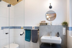 Een moderne badkamer met toilet, wastafel en douche.