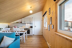 A cozy interior with a wooden ceiling, a dining area, a kitchen, and a large window.