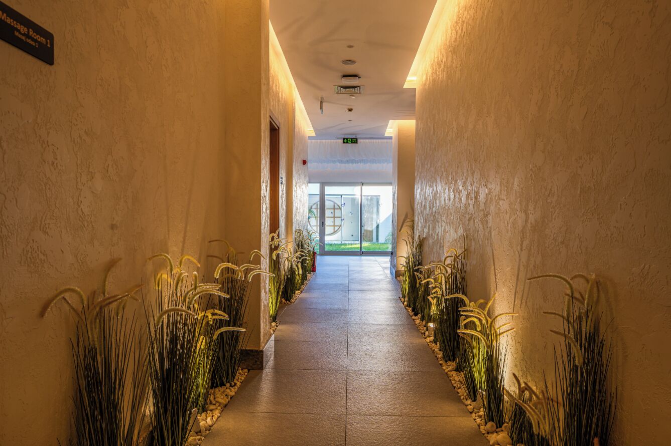 A hallway with a sign for Massage Room 1, leading to a glass door entrance.