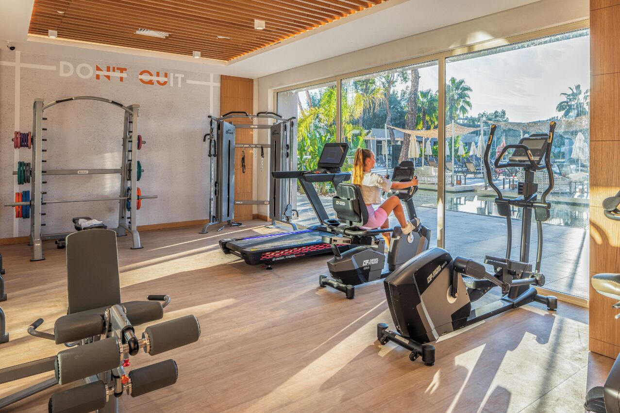 A modern gym with cardio machines, weightlifting equipment, and a motivational wall saying "DON'T QUIT".