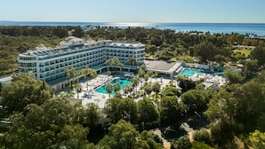 A large hotel with multiple floors, a central courtyard with a swimming pool, and a view of the sea. - Berry Blue Hotels - All Inclusive (Manavgat)