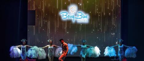 A stage performance with a backdrop displaying "Berry Blue Hotel".