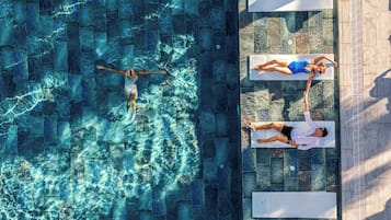 An aerial view of a swimming pool with two lounge chairs and a person swimming.
