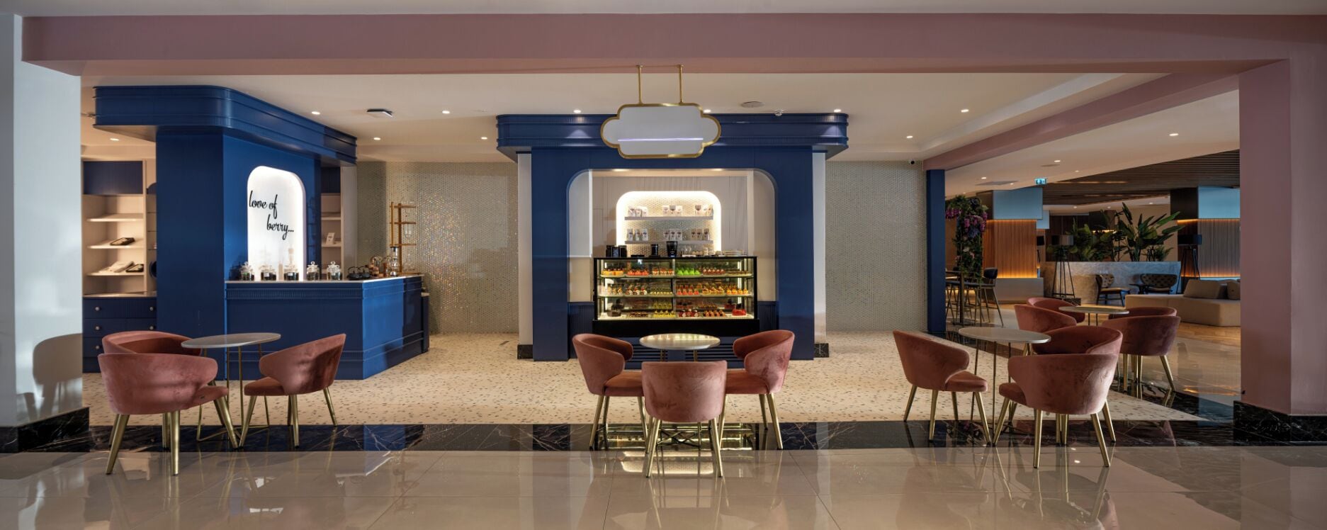 A modern hotel lobby with a central bar area, seating arrangements, and a decorative wall with a sign.