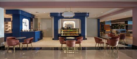 A modern hotel lobby with a central bar area, seating arrangements, and a decorative wall with a sign.