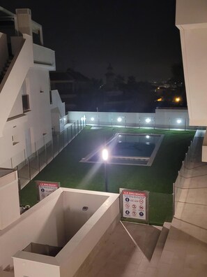 Enjoy a refreshing swim under the stars at this rooftop pool, surrounded by a glass barrier and illuminated by multiple lights.