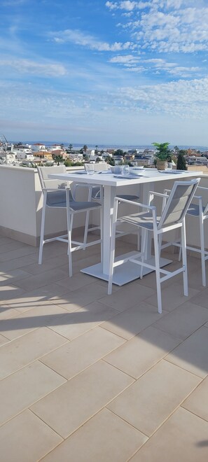 Enjoy a tranquil moment on this outdoor space with a table and chairs, surrounded by the sights of a charming coastal town.