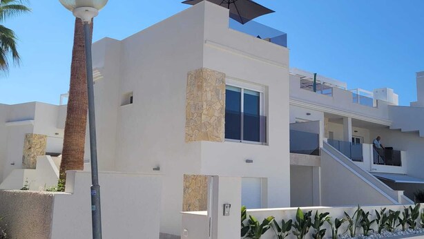 A modern building with a white facade, stone accents, and a staircase leading to an upper level. - Penthouses Blue Lagoon (VC)
