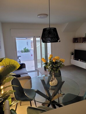 Enjoy meals at the glass dining table surrounded by four chairs, with a view of the outside through the large window.