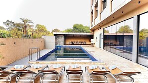 A rooftop pool area with lounge chairs and a seating area. - Pride Elite Daman (Daman)