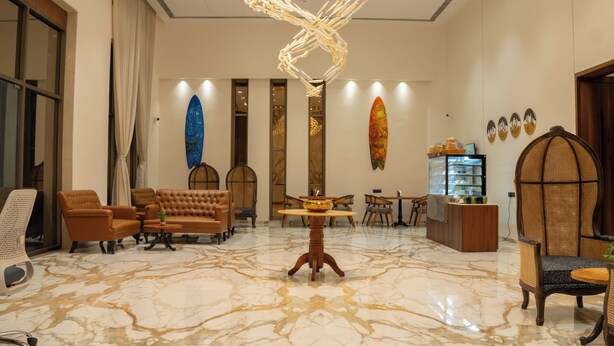 A spacious lobby with a marble floor, leather seating, a central table, and a unique ceiling sculpture. - Pride Elite Daman (Daman)