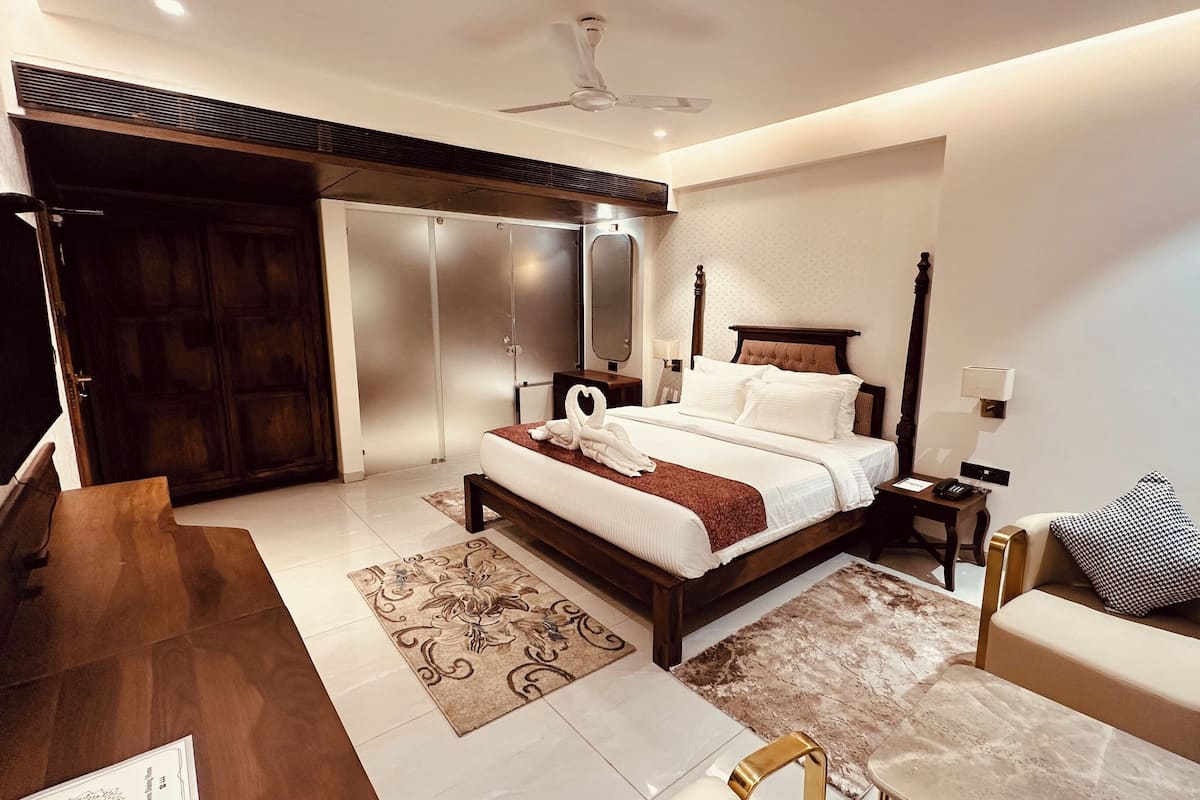 A modern hotel room with a large bed, a desk, a chair, a wardrobe, and a ceiling fan.