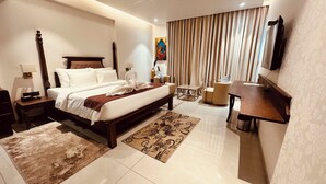 Una habitación de hotel con una cama grande, un escritorio, una silla, un televisor y un cuadro en la pared.