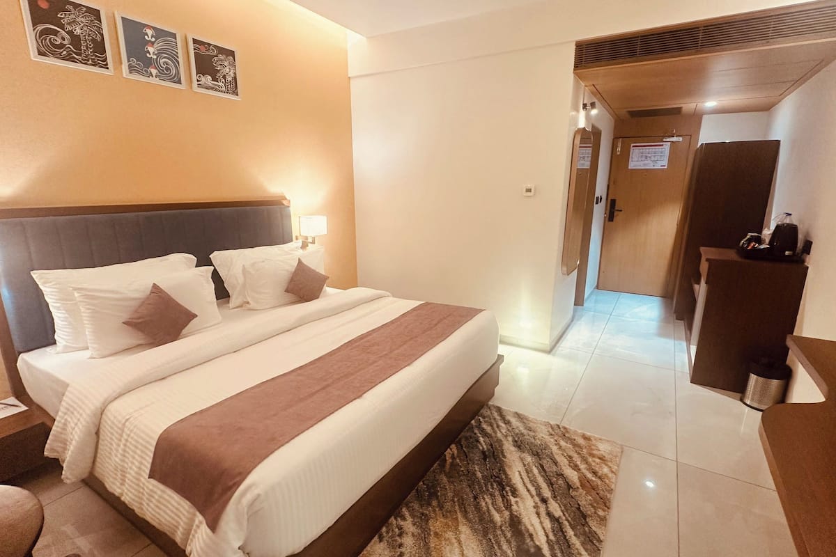 A hotel room with a large bed, bedside tables, a desk, and a mirror.