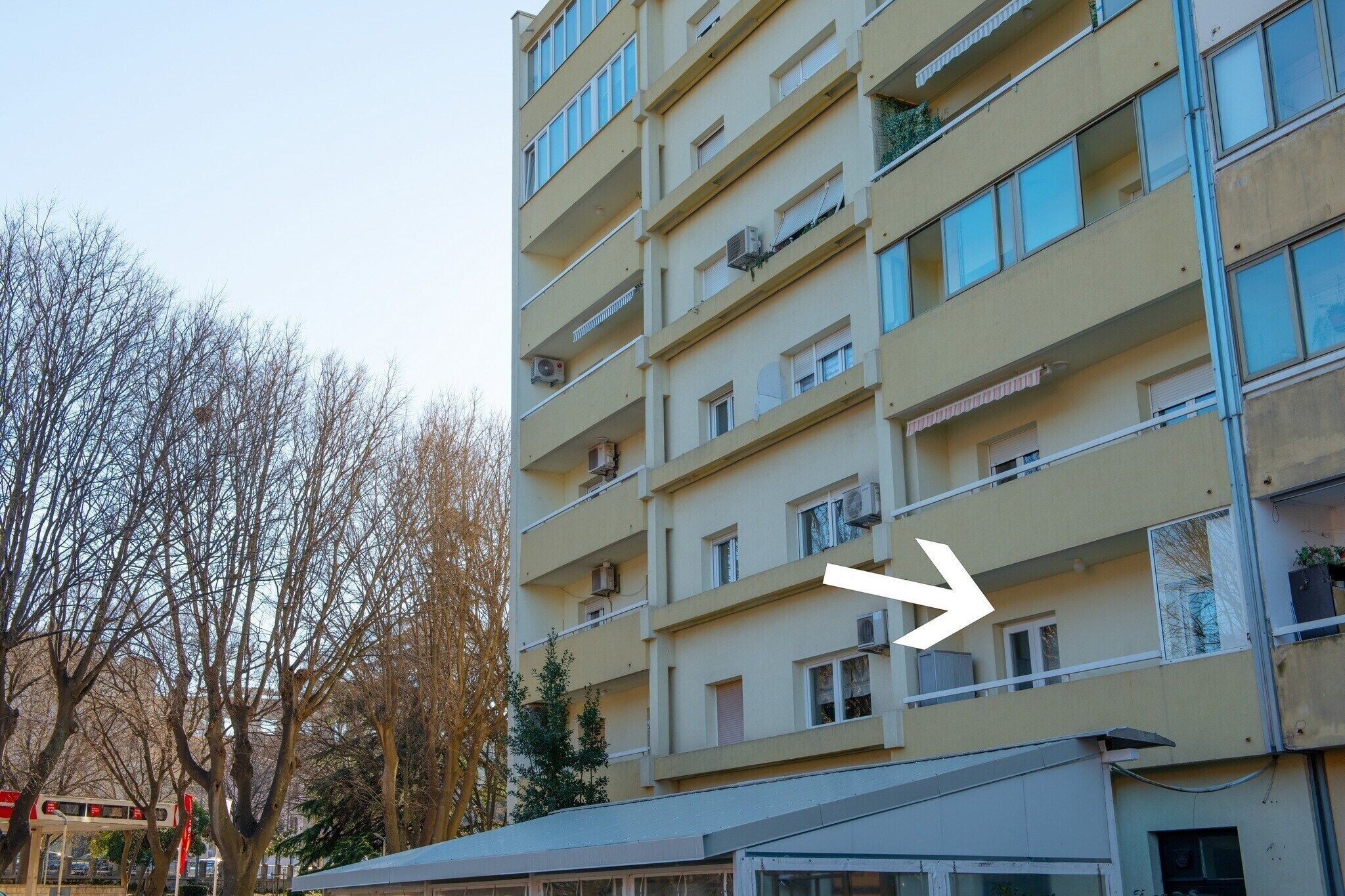 Un edificio residencial de varios pisos con balcones, unidades de aire acondicionado y un cielo despejado.