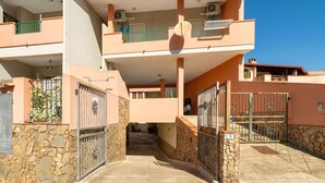 A two-story building with a stone facade, a gated entrance, and a clear sky. - Beautiful apartment in villa for 8 people with A/C, TV, balcony and panoramic view (Villasimius)