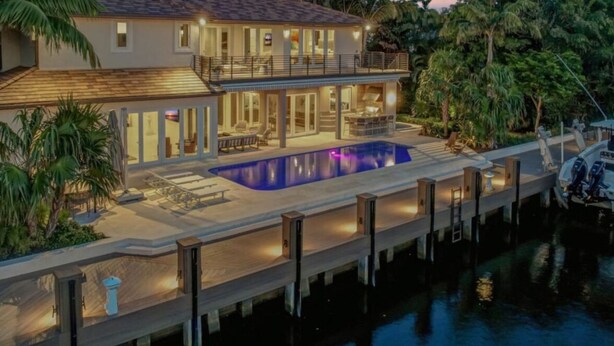 Une maison à deux étages avec une piscine, un quai et un bateau.