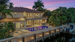Une maison à deux étages avec une piscine, un quai et un bateau.