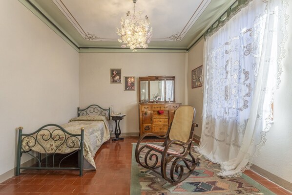 Une chambre à coucher avec un lit, une chaise, une commode et un lustre.