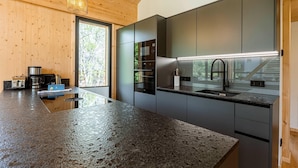 A modern kitchen with a granite countertop, stainless steel appliances, and a large window providing a view of the outdoors.