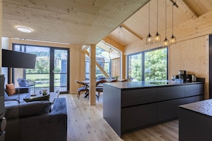 A modern kitchen with a large island, wooden beams, and pendant lighting.