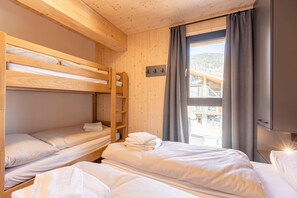 Una habitación con literas, una ventana con cortinas y vistas a un edificio.