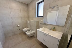 Une salle de bain moderne équipée de toilettes, d’un bidet et d’un lavabo.