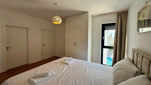 A hotel room with a large bed, a wardrobe, and a window with a view of buildings. - Apartment in Croatia near the Adriatic Coast (Crikvenica)