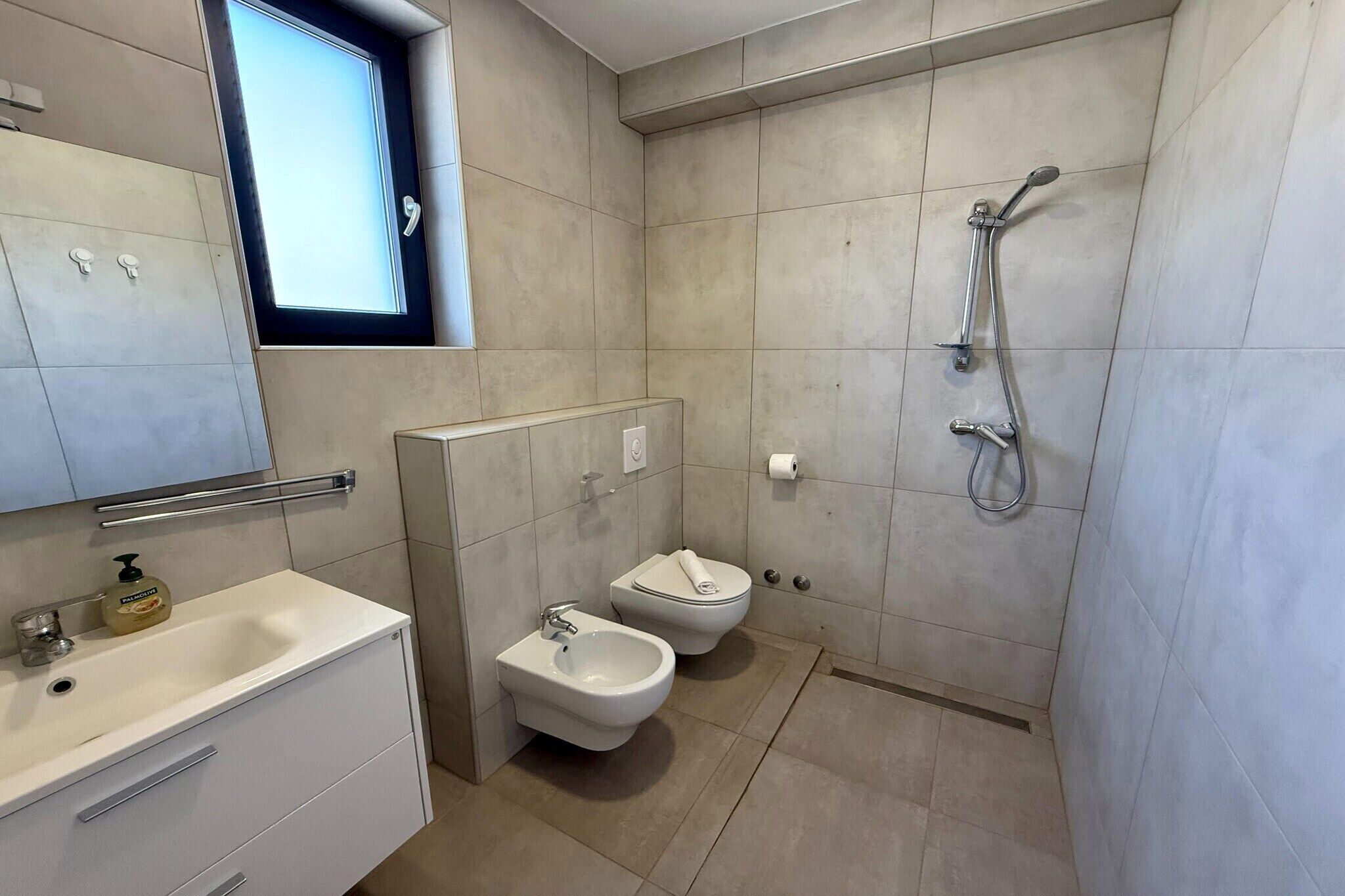 Ein modernes Badezimmer mit Toilette, Bidet, Waschbecken und Dusche.