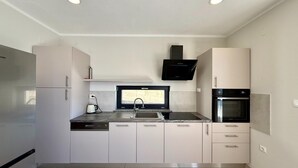 A modern kitchen with white cabinets, a built-in oven, a microwave, and a dishwasher. - Apartment in Croatia near the Adriatic Coast (Crikvenica)