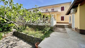 Un cortile con un muro in pietra, un piccolo albero e un edificio con un balcone.