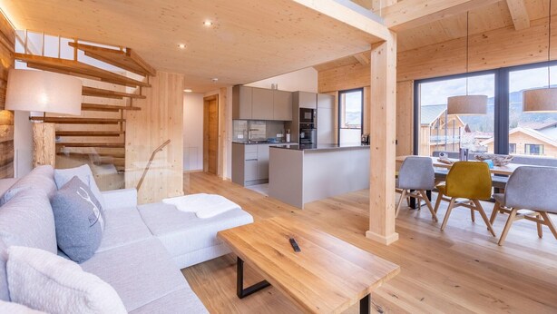 Un interior moderno con techo de madera, una zona de cocina y un área de estar con sofá y sillones.