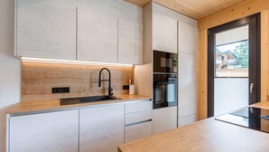 Eine moderne Küche mit einer Holz Arbeitsplatte, Edelstahlgeräten und einem eingebauten Backofen.