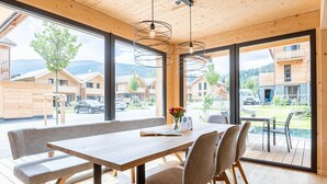 Ein moderner Essbereich mit Holztisch und Bank, großen Fenstern und Blick auf eine Wohngegend.