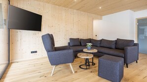 Ein modernes Wohnzimmer mit einem Ecksofa, einem runden Couchtisch und einem flachbildfernseher an der Wand.