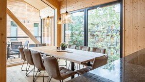 Un espace repas moderne avec une grande table en bois, des chaises confortables et des luminaires suspendus.