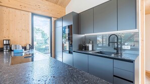 Eine moderne Küche mit grauen Schränken, einer Arbeitsplatte aus Granit und einem Fenster mit Blick auf eine Wohngegend.