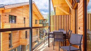 Eine moderne Holz-Blockhütte mit Balkon, großen Fenstern und Essbereich.