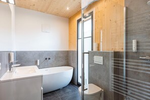 Une salle de bain moderne avec une baignoire sur pieds, des toilettes et une douche à parois de verre.