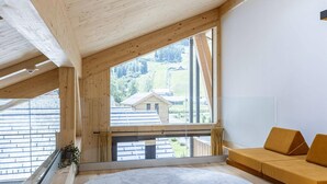 Un'ampia stanza con una grande finestra, un soffitto in legno e un divano.