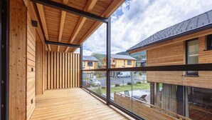 Una terrazza in legno con parete di vetro che si affaccia su una zona residenziale.