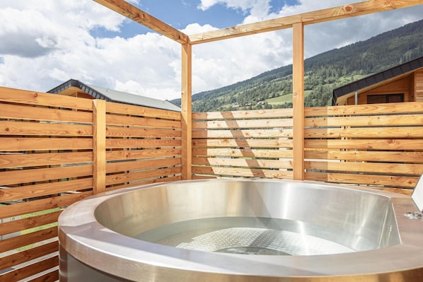 A hot tub in a wooden cabin with a view of mountains.