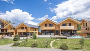 Een rij houten vakantiehuisjes met zwembad en een terras.