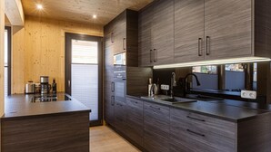 Een moderne keuken met donkerhouten kasten, een roestvrijstalen aanrecht en verlichting onder de kast.