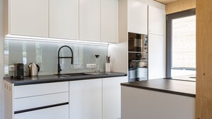 Uma cozinha moderna com armários brancos, bancada preta e eletrodomésticos de aço inoxidável.