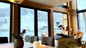 A cozy interior with large windows, wooden walls, and a view of a snowy landscape. - Panorama holiday home with sauna (No Deposit) (Sankt Georgen am Kreischberg)