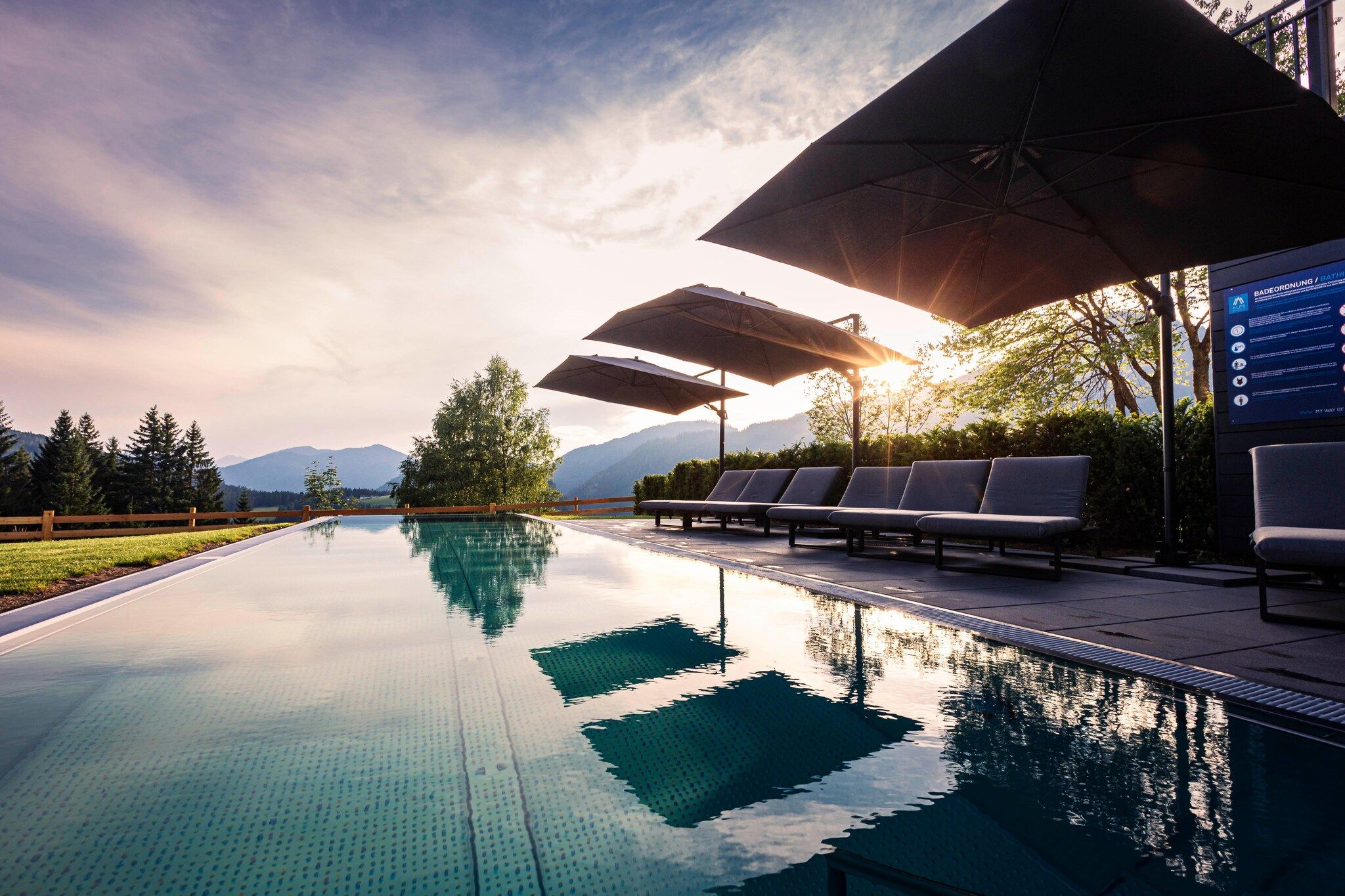 Ein Infinity-Pool mit Blick auf Berge, Liegestühlen und Sonnenschirmen.