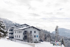 A modern building with multiple floors, a ski lift, and a snowy mountain backdrop.